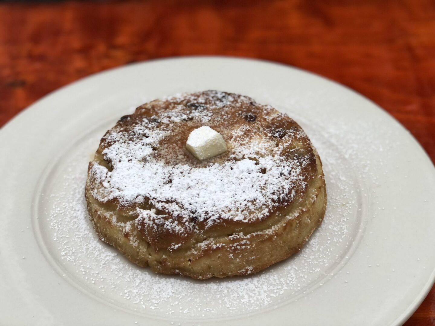 A white plate topped with a pastry covered in powdered sugar.