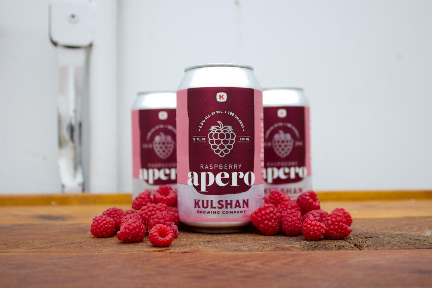 Three cans of raspberry flavored beer sitting on a table.