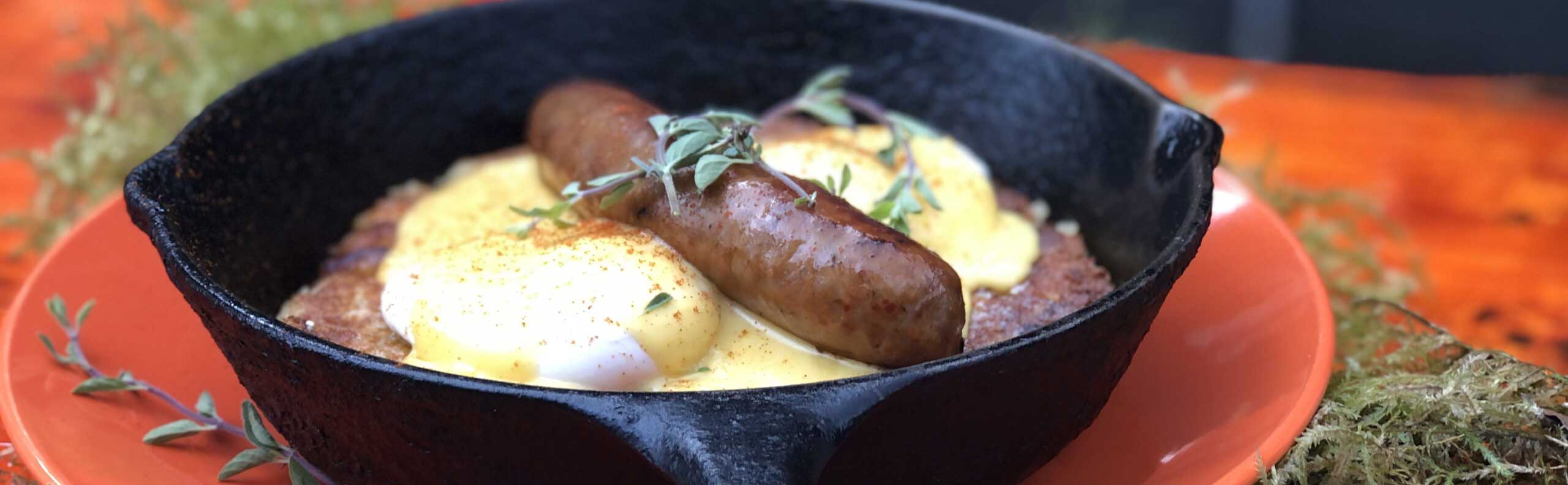 A sausage and eggs in a pan with herbs.