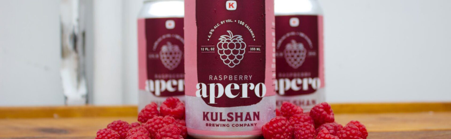A can of raspberry apero beer sitting on top of raspberries.