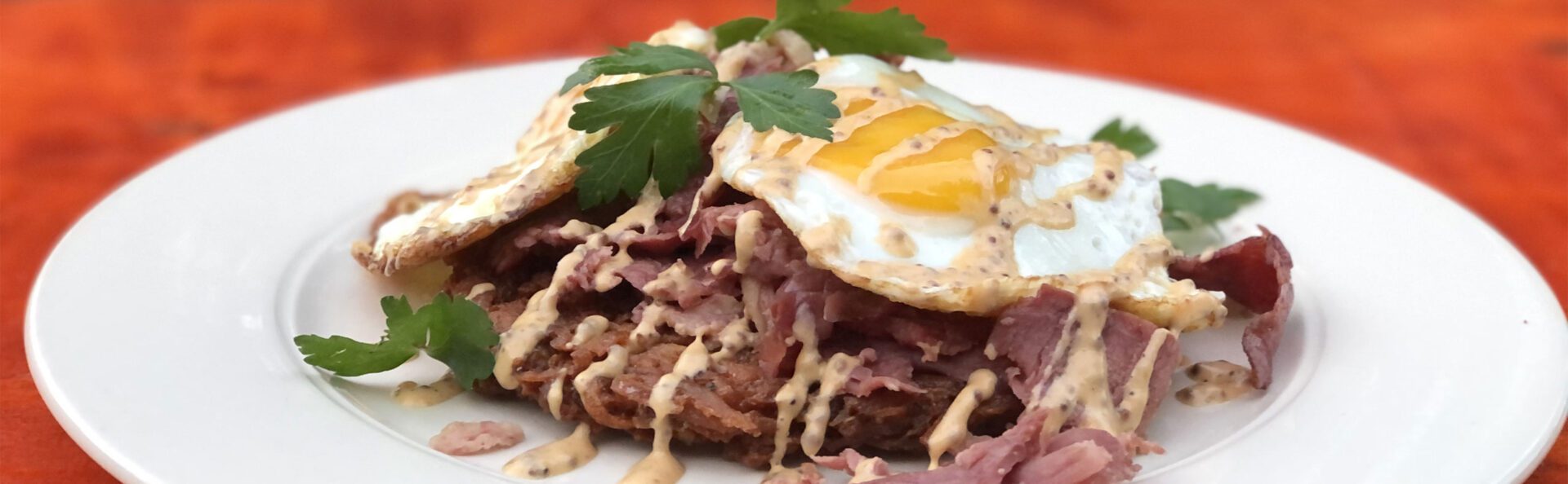 A plate of food with meat and an egg on top.