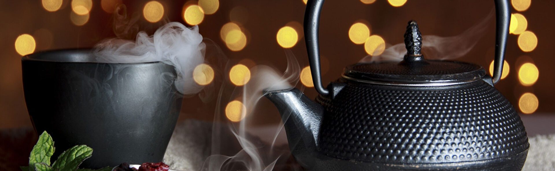 A black tea pot with steam coming out of it.
