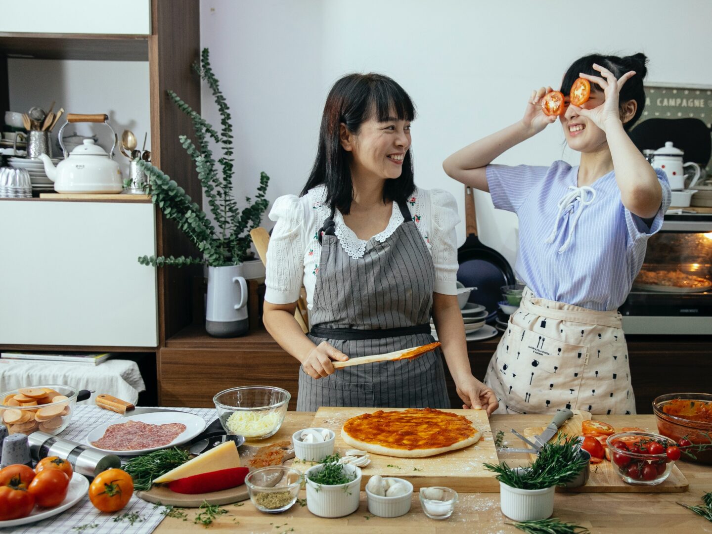 Two women standing in front of a table with food.
