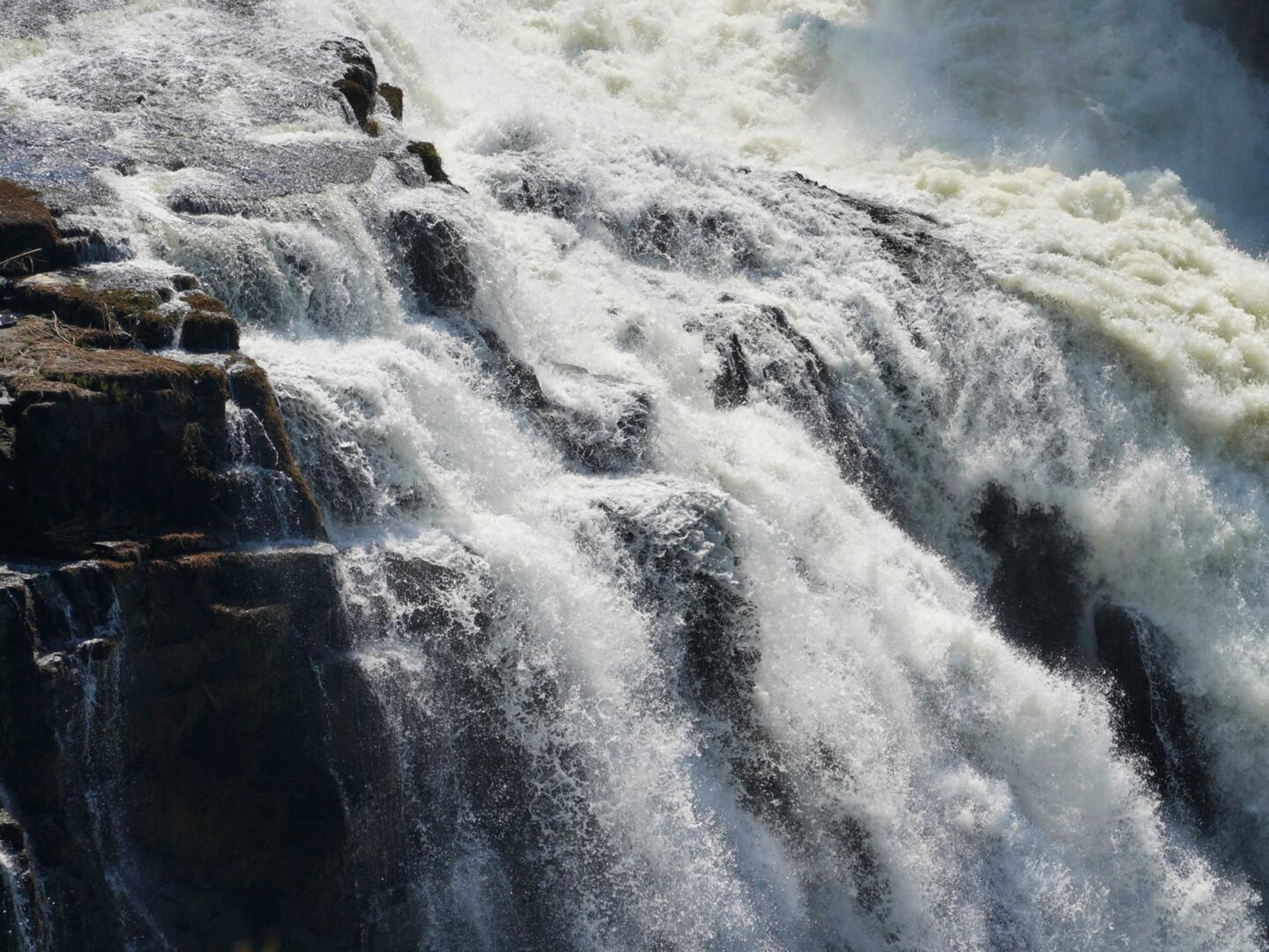 A person is standing on the side of a waterfall.