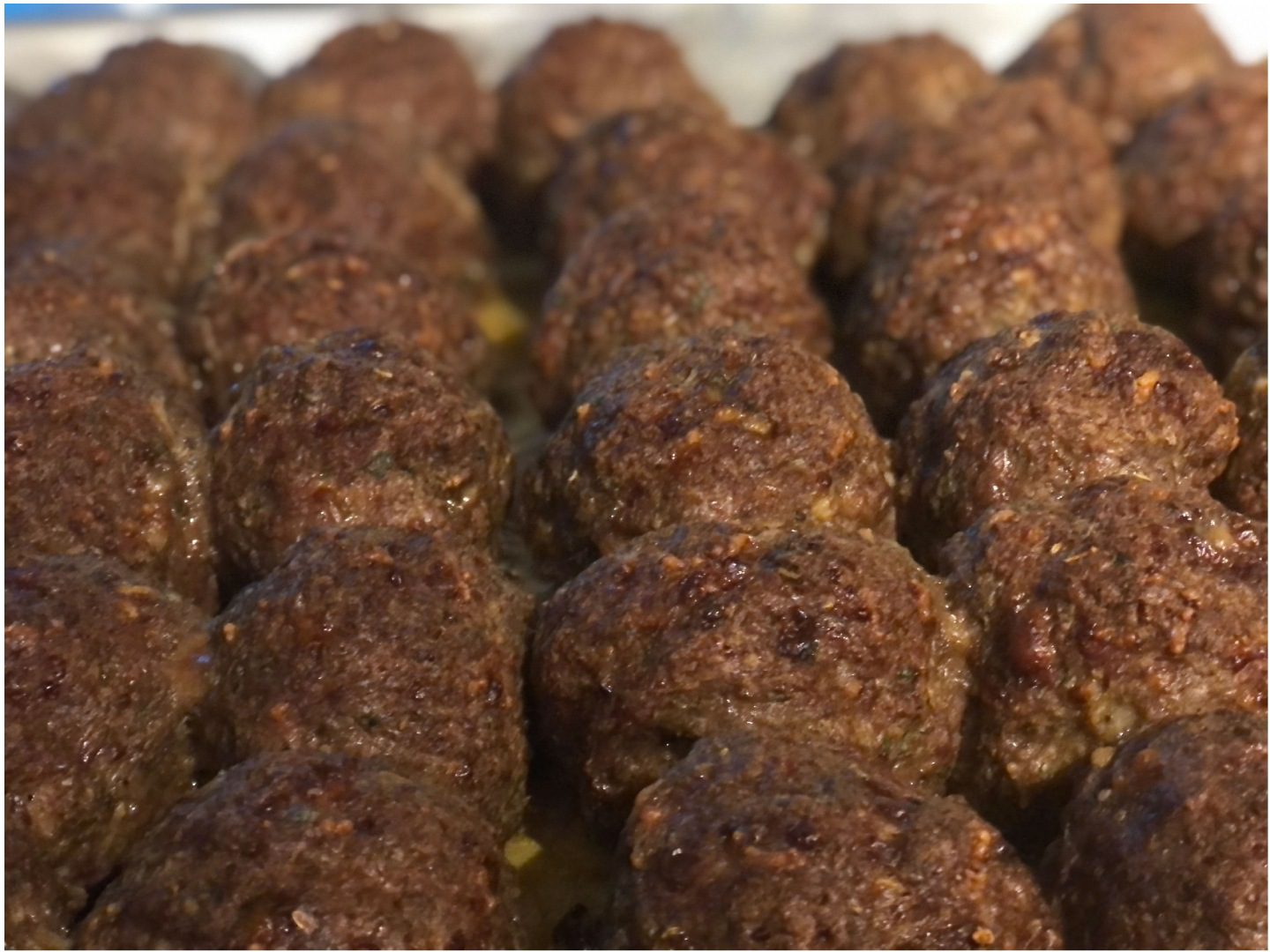 A close up of many meatballs in the pan