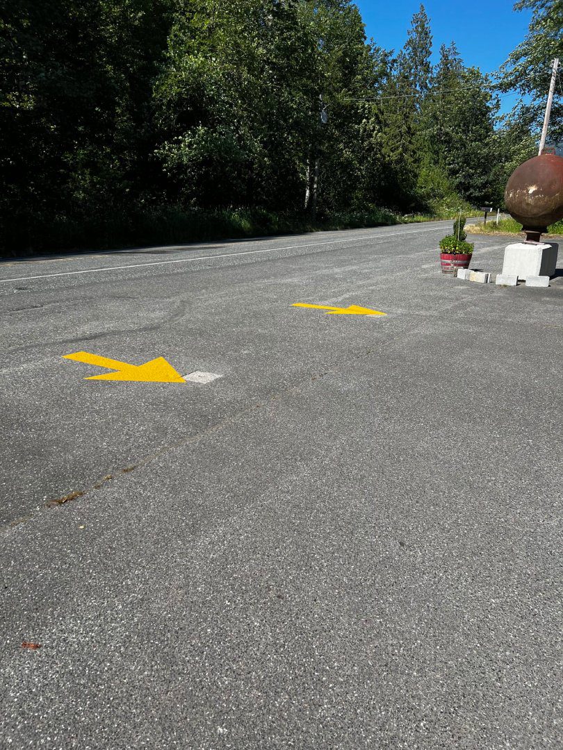 A street with yellow arrows painted on the ground.