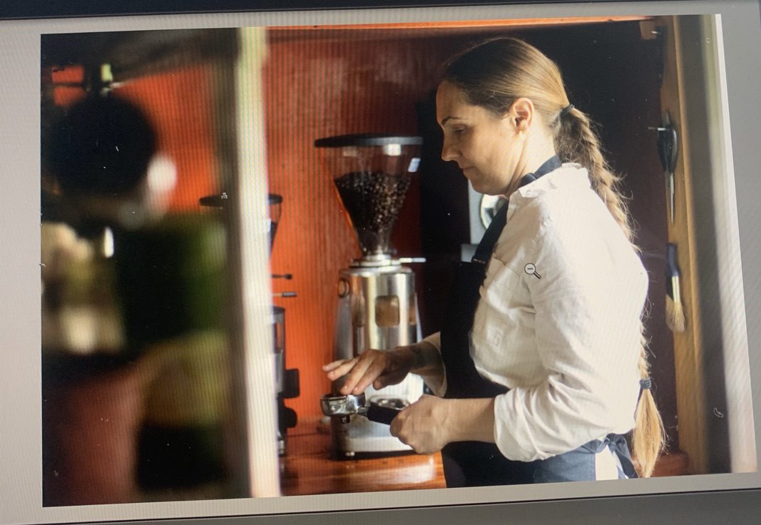 A woman is standing in front of a coffee maker.